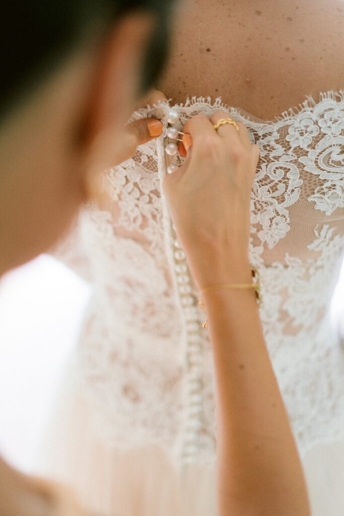 destination wedding in Italy - mother of the bride helping her button her wedding dress for a romantic outdoor ceremony