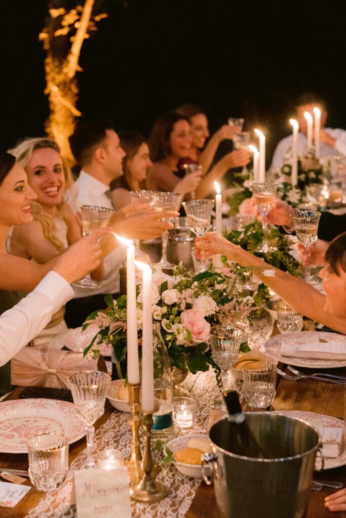 guests ckicking their glasses for a candle lit romantic wedding in italy by atelier crespi wedding planner