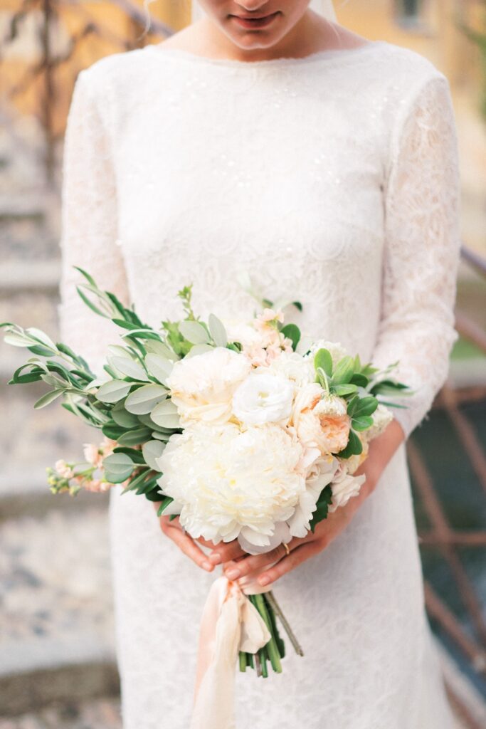 bride holding blush and white wedding flowers