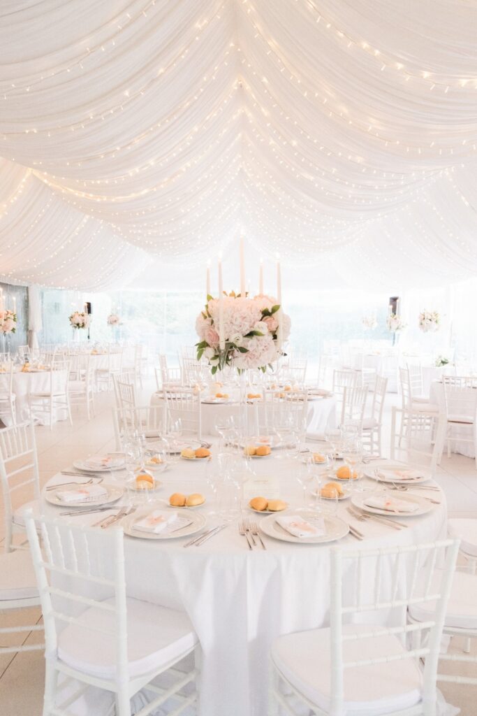 white and pink wedding dinner setting with round tables, pink roses arrangements, candles and fairylights planner by wedding planner in italy atelier crespi