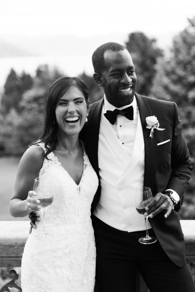 black and white photography of bride and groom holding a glass of white wine at their wedding dinner planned by atelier crespi wedding planner in italy