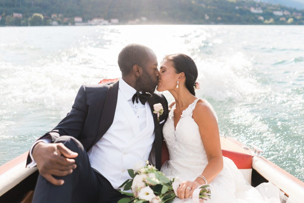bride and groom kissing on a boat in lake como after their wedding ceremony
